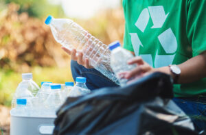 volunteer picks up plant-based plastic bottles for recycling