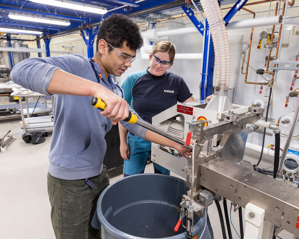 A student learns how to use the Buhler extruder at the Integrated Bioprocessing Research Laboratory